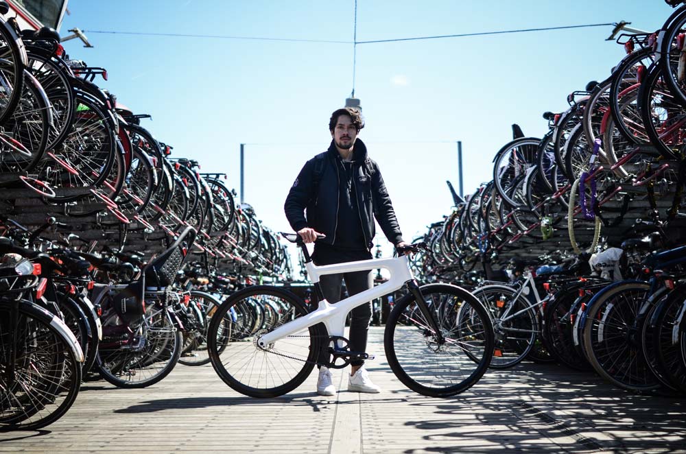 Man holding white bike with rows of bikes on either side